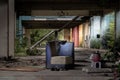 The old blue upholstered chair is in the middle of the abandoned buildings, it was left over years