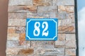 Old blue vintage house address metal plate number 82 on the decorative brick facade of residential building exterior wall on the s Royalty Free Stock Photo