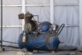 An old blue Working mobile air compressor for painting walls on a construction site. Engineering equipment Royalty Free Stock Photo