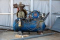 An old blue Working mobile air compressor for painting walls on a construction site. Engineering equipment Royalty Free Stock Photo