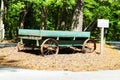 An old bluish green wooden wagon with rusty wheels surrounded by lush green trees at Newman Wetlands Center