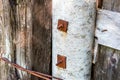 Old boards are fastened with rusty bolts with nuts and washers to the concrete pillar Royalty Free Stock Photo