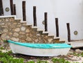 Old boat on beach by rock stairs and white wall Yucatan Mexico