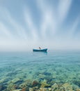 An old boat with one man abandoned sailing through the strange calm still sea Royalty Free Stock Photo