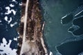 Old boat ship, trapped, frozen in winter ice lake, docked in pier, aerial top down view Royalty Free Stock Photo