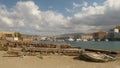 Old boat sprawling and gangway lying on the sand against the background of the promenade of Chania