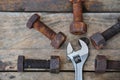 Old bolts with adjustable wrench tools on wooden background