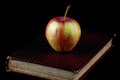 Old Book and Apple on a Black Background Royalty Free Stock Photo