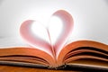 Old book and heart-shaped pages. White background. Wooden Table. Closeup Royalty Free Stock Photo