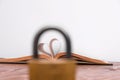 Old book and heart-shaped pages. White background. Wooden Table. Copy space. View through a padlock