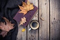 Old book, knitted sweater with autumn leaves and coffee mug