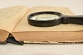 Old book with magnifying glass, white background Royalty Free Stock Photo