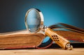 Old book and magnifying glass on wooden table Royalty Free Stock Photo