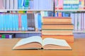 old book open in school library on wooden table. blurry bookshelves background