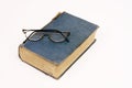 Old book with reading glasses resting on white Royalty Free Stock Photo