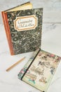 Old book with recipes in French and notebook for writing with pen on white marble