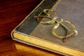 Old Book and Spectacles on a Polished Wooden Table Top Royalty Free Stock Photo