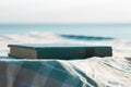 An old book on a table on blue sea lanscape background. Literature reading and relax on the beach, summer vacations Royalty Free Stock Photo