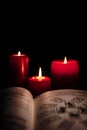 Old book with tarot cards and red candles in front of black background, reading horoscope and fortune Royalty Free Stock Photo
