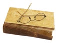 On an old book with a torn binding and a broken spine are glasses
