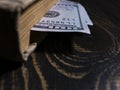 Old book and two hundred dollars bookmark in a thick book. book on the background of a wooden table Royalty Free Stock Photo