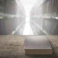 Old book on wooden table with blur bookshelfs background