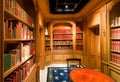 Old books on bookshelves with volumes and antique wooden table inside the library