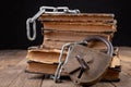 Old books bound by a new shiny chain with an old padlock. Forbidden old works artists on a wooden table Royalty Free Stock Photo