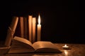 Old books, a burning candle and a scroll on a wooden table on a Royalty Free Stock Photo