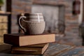 Old books and cup of coffee on wooden grunge table over fireplace background.Composition with stack of books and cup of Royalty Free Stock Photo