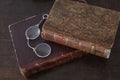 Old books piled on an antique wooden furniture with reading glasses Royalty Free Stock Photo