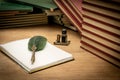 Old books stacked in disarray, an old pen with its ink and a notepad on an old wooden table and dim lighting. Selective focus. Royalty Free Stock Photo