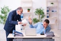 Old boss and his young assistant in the office Royalty Free Stock Photo