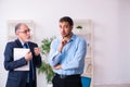 Old boss and his young assistant in the office Royalty Free Stock Photo