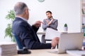 Old boss and his young assistant working in the office Royalty Free Stock Photo