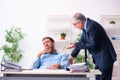 Old boss and his young assistant in the office Royalty Free Stock Photo