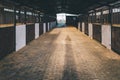 Old box for animals in an empty stable with bars and wooden doors for horses