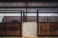 Old box for animals in an empty stable with bars and wooden doors for horses