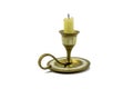 An old brass candle holder with mother-of-pearl inlays, a beautiful curved handle and a partially burnt candle on an isolated