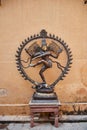 old brass statue of Shiva standing on a wooden vintage small table in front of a patina rich wall in Rajasthan