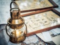 Old brassy ship lantern stands on a map of the seas near pictures with the image of sea knots Royalty Free Stock Photo