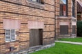 Old brick apartment building with basement windows filled with mixed bricks, vents, and wood boards Royalty Free Stock Photo