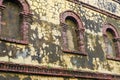 Old brick arched windows against the cracked mossy yellow wall