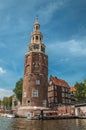 Old brick bell tower and buildings near the tree-lined canal with moored boats and blue sky in Amsterdam. Royalty Free Stock Photo