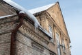 Old brick building covered in snow of heavy snowfall. Hanging icicles from the roof of a residential building. View of the red Royalty Free Stock Photo