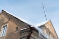 Old brick building covered in snow of heavy snowfall. Hanging icicles from the roof of a residential building. View of the red Royalty Free Stock Photo