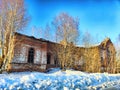 Old brick building partially collapsed in snowy landscape with bare trees during clear winter day Royalty Free Stock Photo