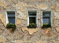 Old brick building wall with damaged plaster and three windows Royalty Free Stock Photo