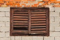 Old brick building wall with window covered with closed wooden blinds, broken Royalty Free Stock Photo