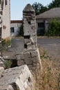 Abandoned courtyard with collapsing buildings and a fence, trees, shrubs, dry grass, clutter on a bright day Royalty Free Stock Photo